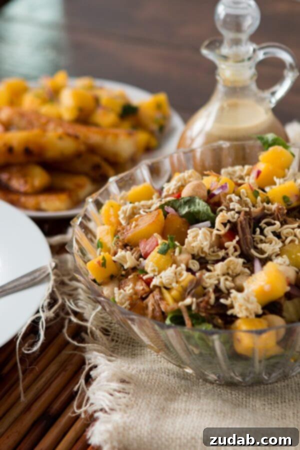 Crunchy Polynesian Pork Salad with Mango Salsa and Grilled Pineapple A large bowl of vibrant Crunchy Polynesian Pork Salad featuring shredded pork, golden grilled pineapple, and colorful mango salsa, drizzled with a creamy dressing. ohsweetbasil.com