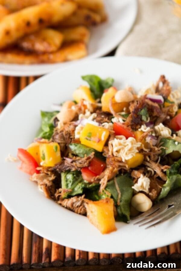Delicious Crunchy Polynesian Pork Salad A full bowl of Crunchy Polynesian Pork Salad, highlighting the crisp romaine, tender pork, and golden grilled pineapple. ohsweetbasil.com