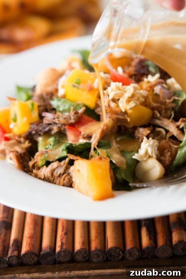Polynesian Pork Salad Dressing The Crunchy Polynesian Pork Salad dressing being poured over a portion of the salad, highlighting its creamy texture and the vibrant colors of the ingredients. ohsweetbasil.com