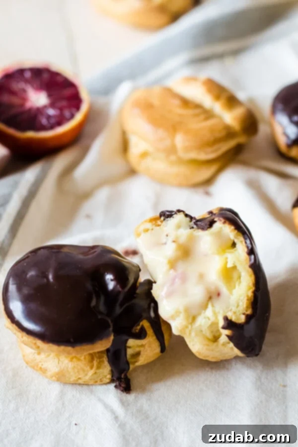 A stunning arrangement of Blood Orange Cream Puffs on a serving platter, showcasing their golden choux pastry, creamy filling, and shiny chocolate topping.