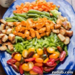 Spicy Buffalo Chicken Creamy Blue Cheese Salad 3 A top-down view of a colorful Buffalo Chicken Salad with chicken pieces, fresh greens, red tomatoes, and other vegetables, generously dressed with creamy blue cheese.