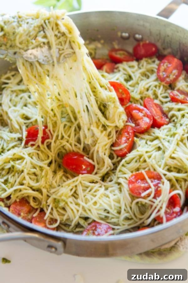 Need dinner on the table in 20 minutes? We've got a 20 minute cheesy pesto pasta recipe that's quick and easy to make and it's a great special diets recipe. Tongs gently pulling a portion of vibrant green pesto pasta from a large, rustic skillet, ready to be served into a bowl.