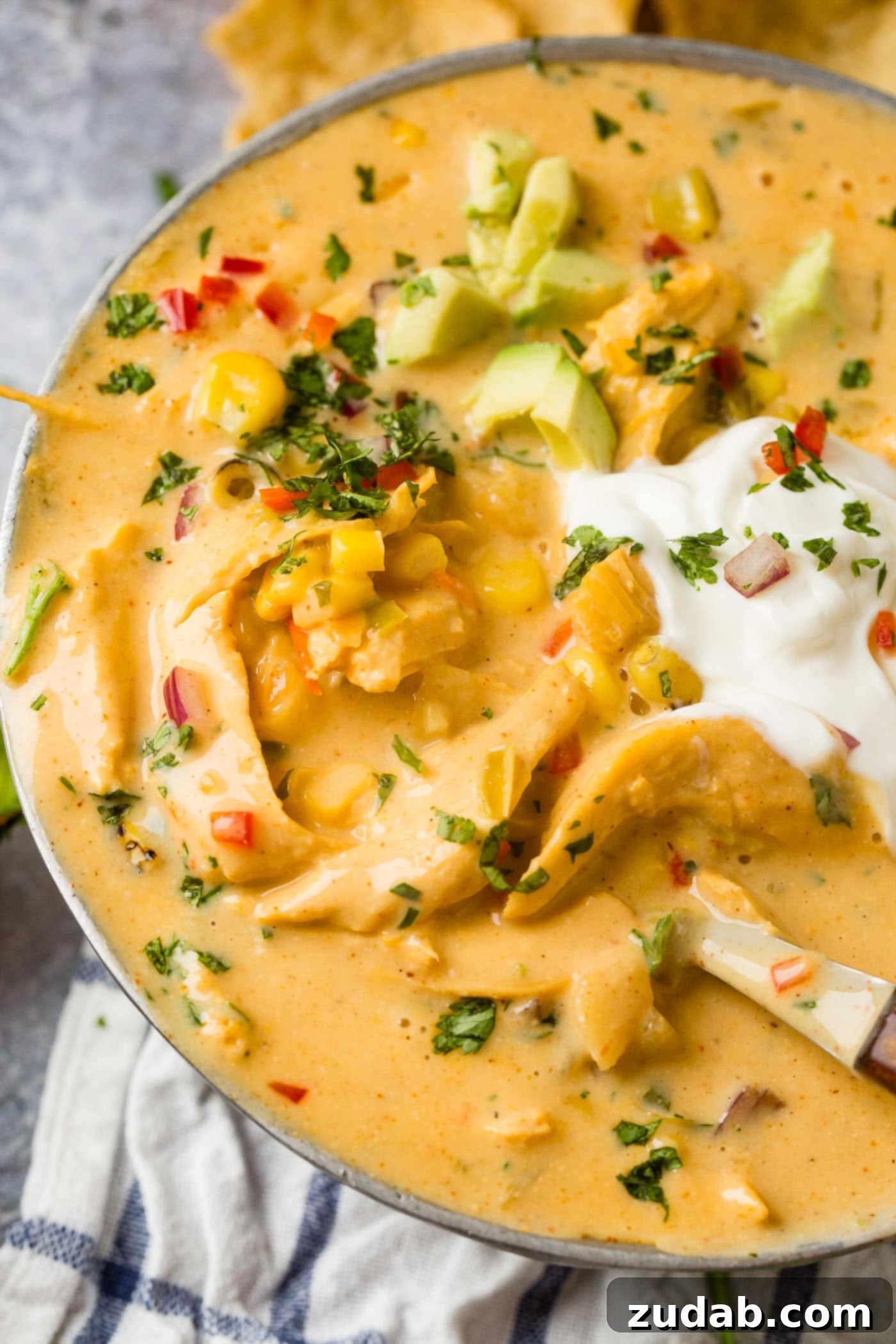 Hearty Cheesy Southwestern Chicken Tortilla Soup 2 A vibrant bowl of Cheesy Southwest Chicken Soup, garnished with a dollop of sour cream and fresh avocado slices, ready to be enjoyed.
