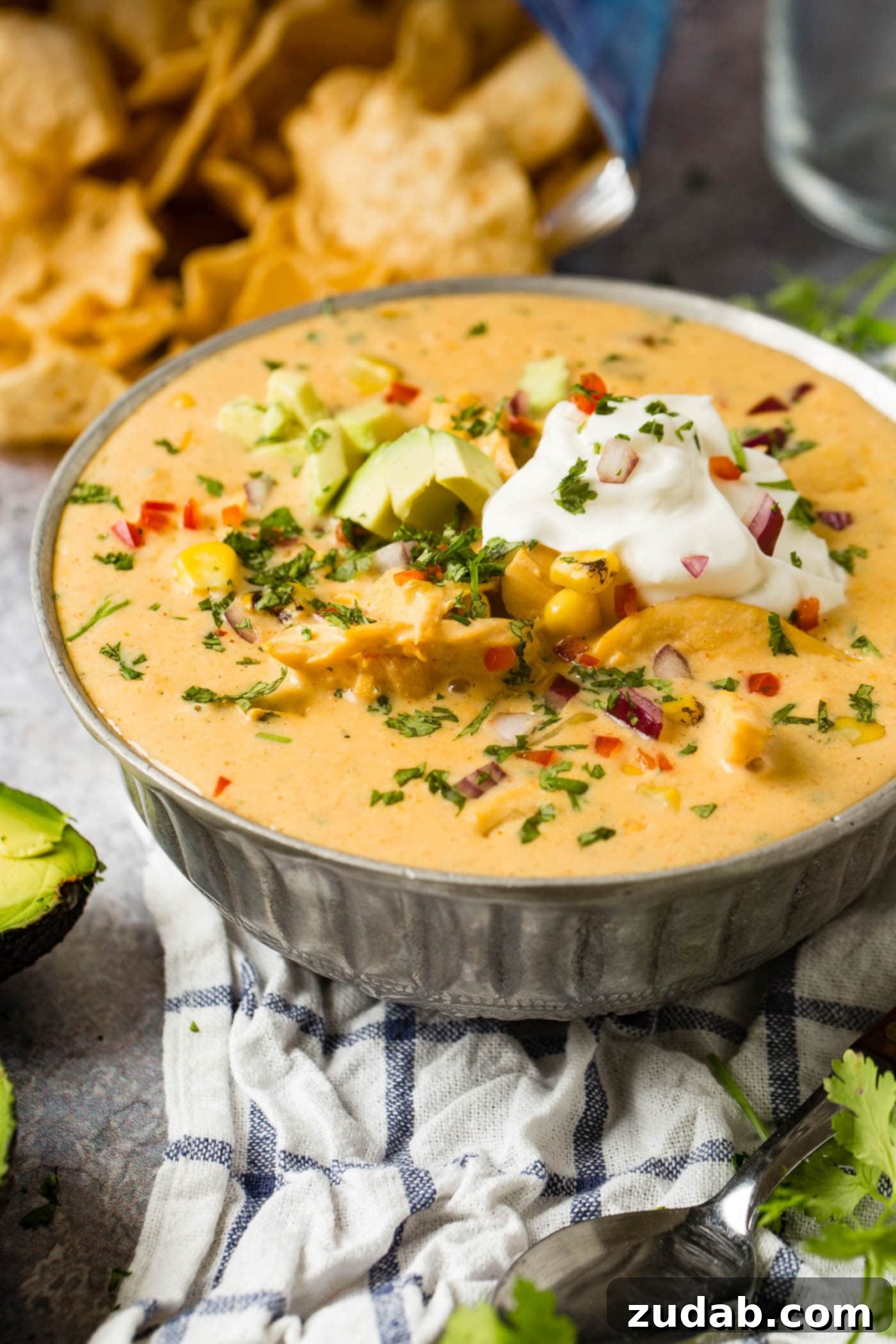 Hearty Cheesy Southwestern Chicken Tortilla Soup 3 A close-up of cheesy chicken tortilla soup, richly textured with sour cream, avocado, and fresh cilantro as toppings.