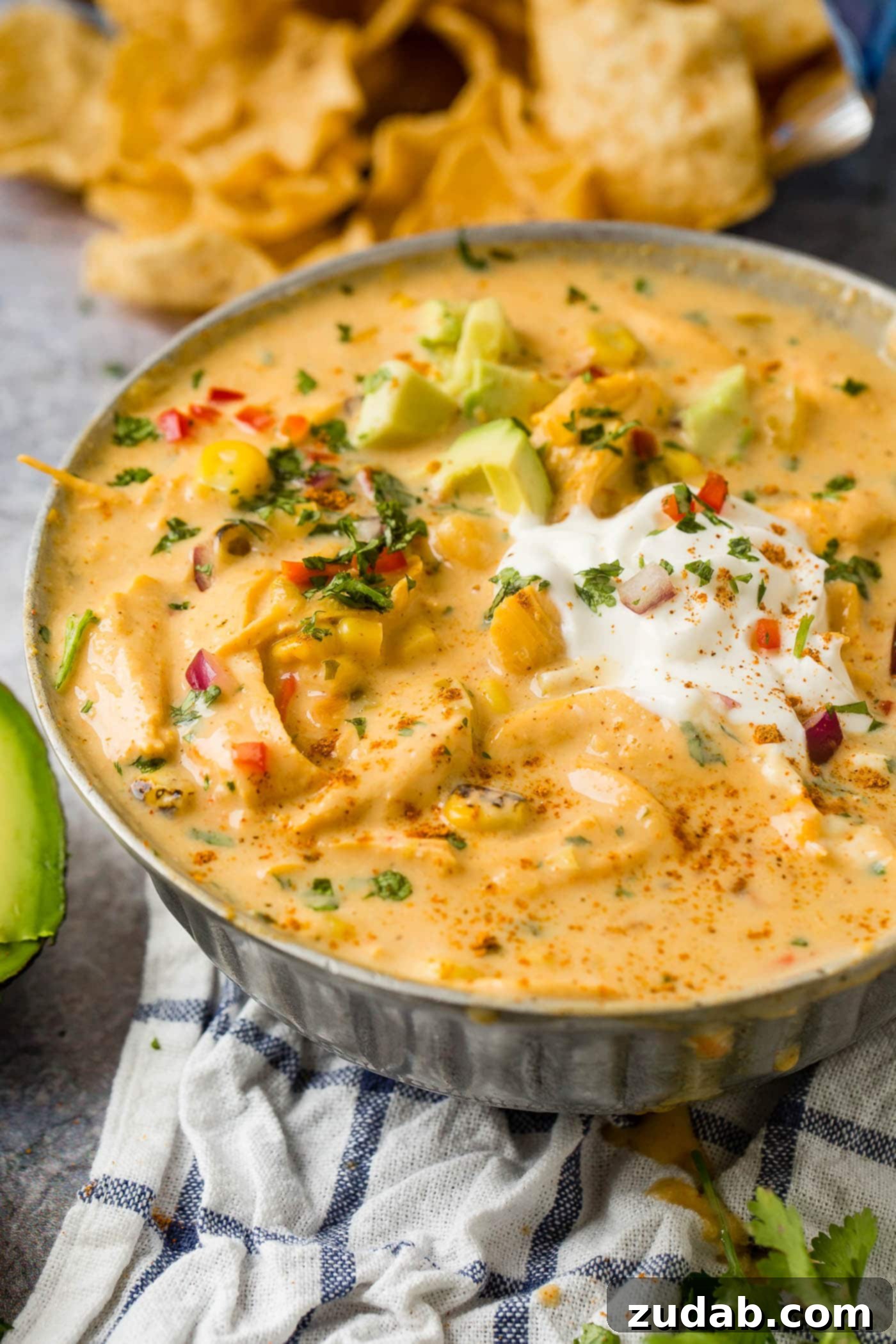 Hearty Cheesy Southwestern Chicken Tortilla Soup 4 A bowl of Cheesy Chicken Tortilla Soup, garnished with a generous dollop of sour cream and perfectly ripe avocado slices.