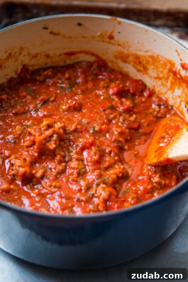 Discover the secret to the most delicious homemade spaghetti sauce recipe – a timeless family favorite perfected over the years. Rich homemade spaghetti sauce bubbling gently in a rustic blue Dutch oven, ready to be served.