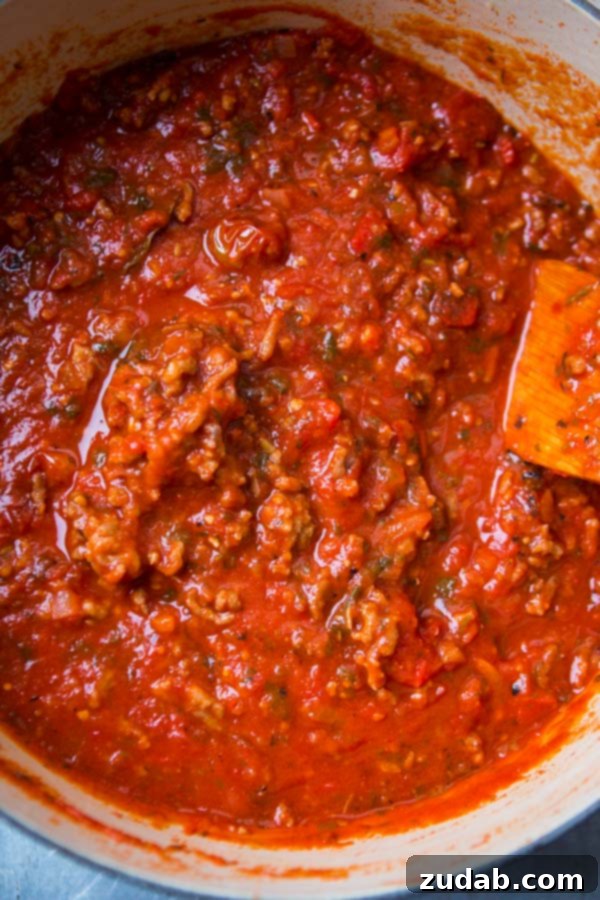 Discover the secret to the most delicious homemade spaghetti sauce recipe – a timeless family favorite perfected over the years. Authentic Italian spaghetti sauce simmering robustly in a large Dutch oven, ready to fill your home with its inviting aroma.