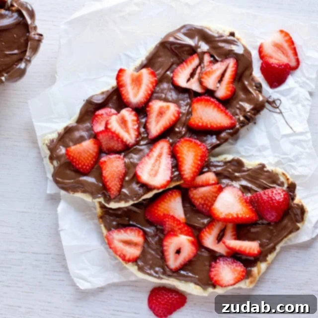 Nutella Strawberry Delight Pizza 3 Close-up of a slice of grilled Naan dessert pizza with melted Nutella and brightly colored strawberries.