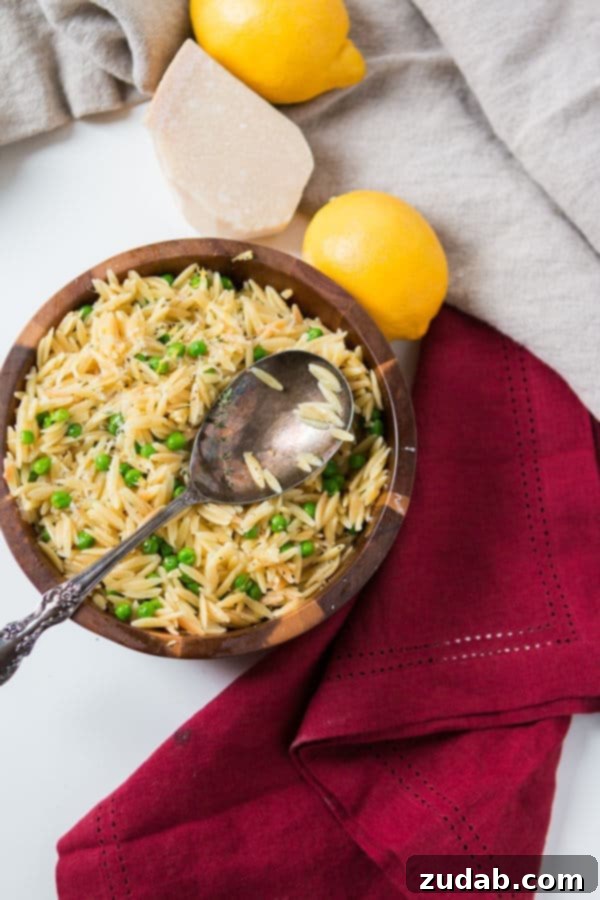 As the winter is starting to melt away we make recipes that scream spring like this Quick and easy lemon orzo with parmesan and peas. Simple lemon orzo with parmesan and peas with a silver spoon next to lemons, parmesan cheese and a red cloth.