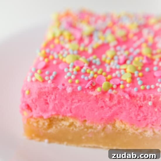 Irresistibly Soft Sugar Cookie Bars with Creamy Frosting A close-up view of frosted sugar cookie bars with sprinkles, ready to be enjoyed.