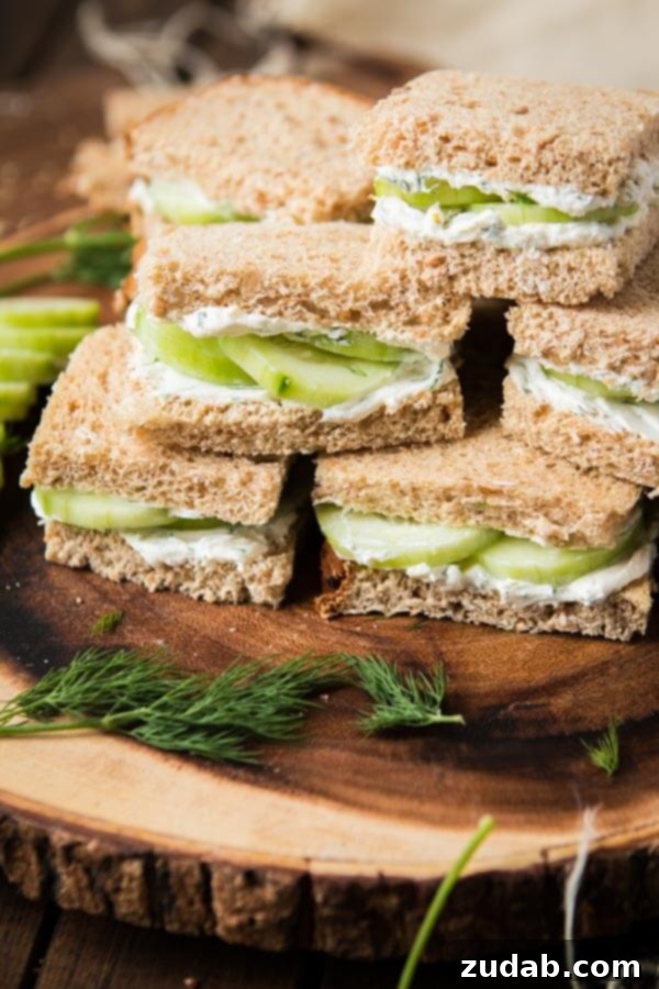 The best lemon dill cucumber sandwiches I've ever had added a touch of Greek yogurt to the spread. Try this awesome tea sandwich recipe at your next party with eureka!® Organic Bread! pile of cucumber sandwiches on serving board