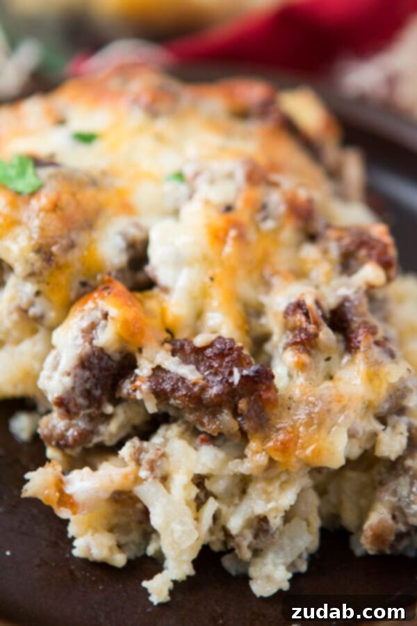A generous portion of cheesy hash brown sausage breakfast casserole served on a rustic gray plate, highlighting its rich textures and golden crust. A generous portion of cheesy hash brown sausage breakfast casserole served on a rustic gray plate, highlighting its rich textures and golden crust.