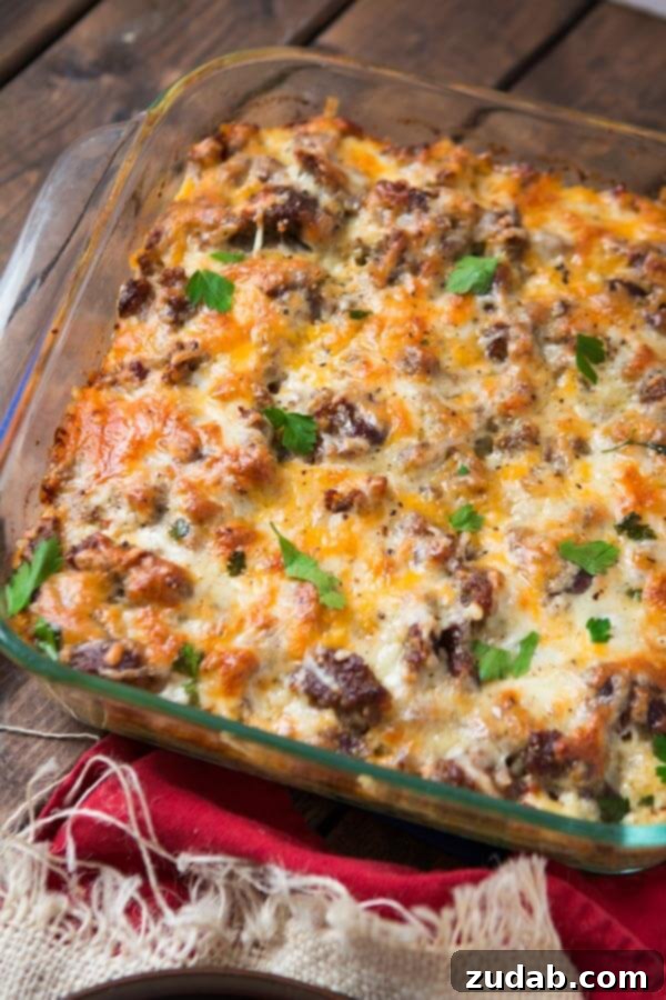 Close-up of the fully baked sausage hash brown breakfast casserole in a square glass baking dish, with crispy edges and melted golden cheese. Close-up of the fully baked sausage hash brown breakfast casserole in a square glass baking dish, with crispy edges and melted golden cheese.