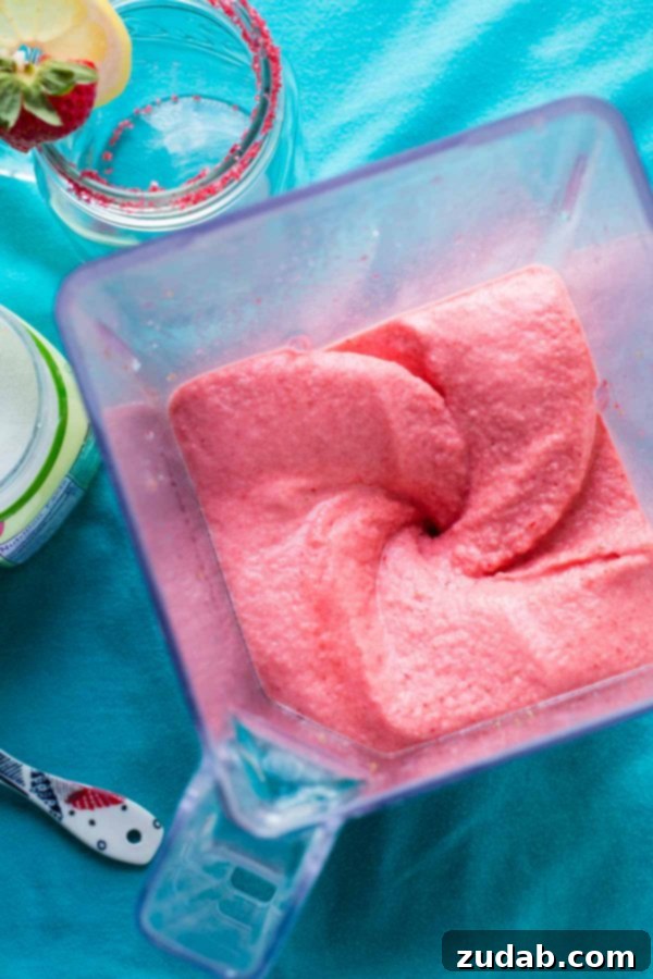 Blended to Perfection: The Making of Frozen Strawberry Lemonade Close-up of a blender filled with fresh lemons, frozen strawberries, and water, ready to be transformed into a refreshing frozen strawberry lemonade.