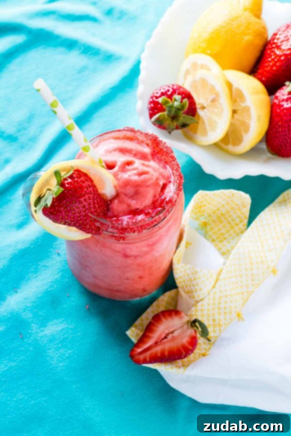 Perfectly Garnished Frozen Strawberry Lemonade - A Summer Delight A close-up of a tall glass of Frozen Strawberry Lemonade garnished with a fresh lemon slice and a whole strawberry, ready to be served.