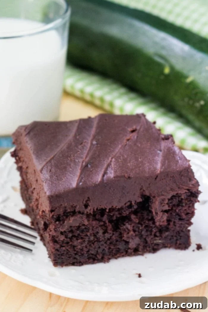 Decadent Double Chocolate Zucchini Cake 4 slice of chocolate zucchini cake on white plate next to glass of milk