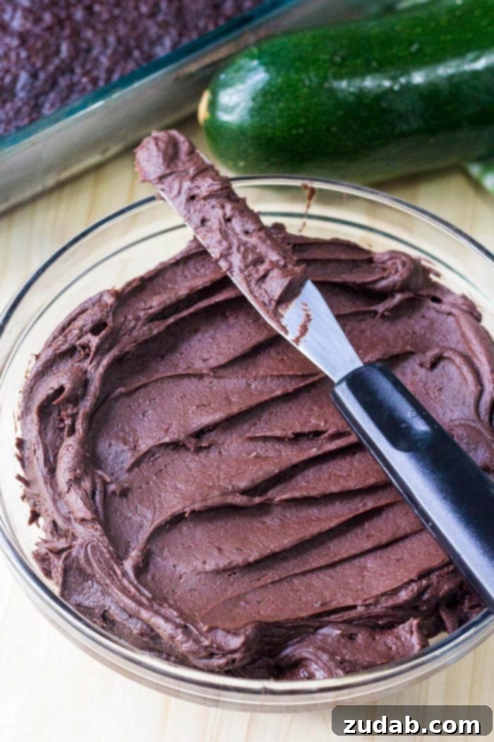 Decadent Double Chocolate Zucchini Cake 5 bowl of homemade chocolate frosting with knife resting on top