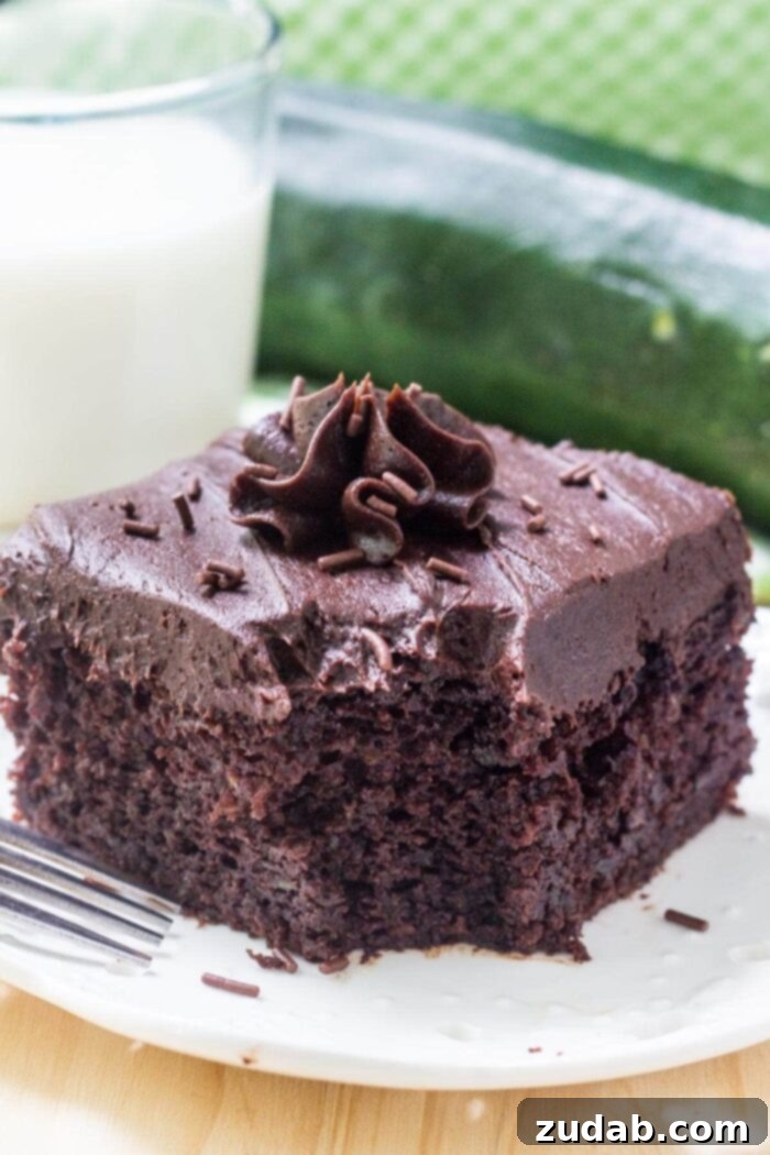 Decadent Double Chocolate Zucchini Cake 6 slice of frosted chocolate zucchini cake on white plate next to glass of milk