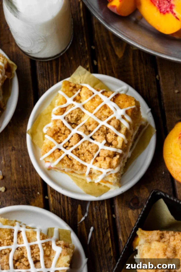 Peach Streusel Coffee Cake 5 a photo taken directly over the top of a piece of peach coffee cake topped with a streusel topping and a vanilla drizzle,