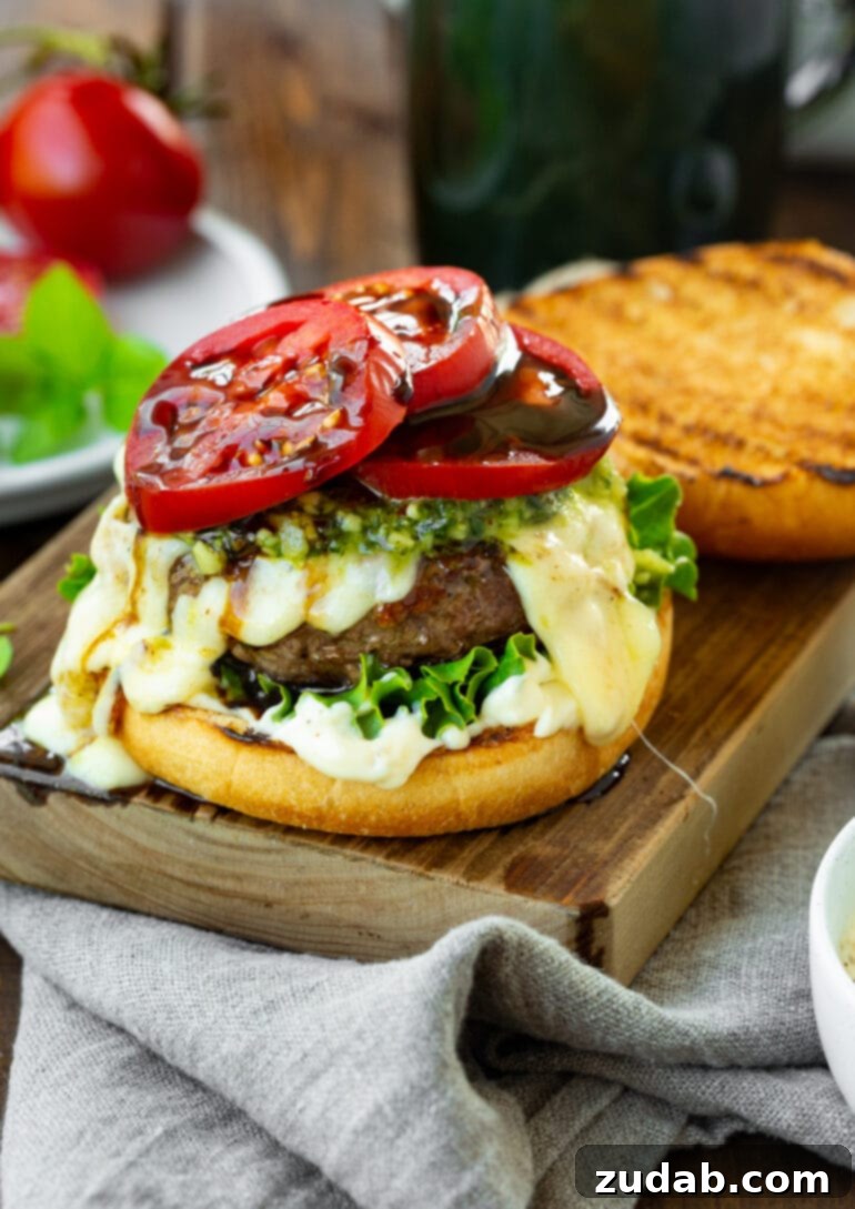 Aromatic Caprese Pesto Burgers 4 A vibrant garlic pesto caprese burger, with the top bun removed to reveal bright red tomato slices generously drizzled with a rich balsamic glaze. A masterpiece of summer grilling.