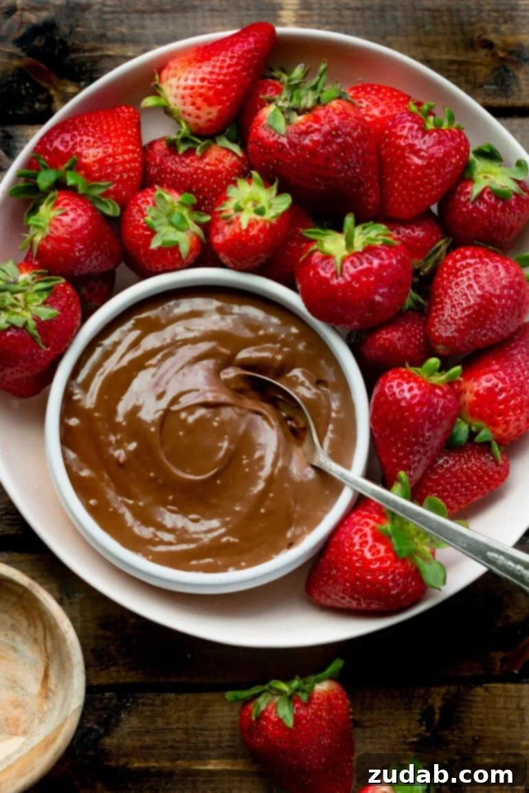 Guilt-Free Chocolate Strawberry Bliss 3 A vibrant platter full of bright red whole strawberries beautifully arranged around a small bowl of creamy chocolate dip, inviting you to indulge in a healthy snack.
