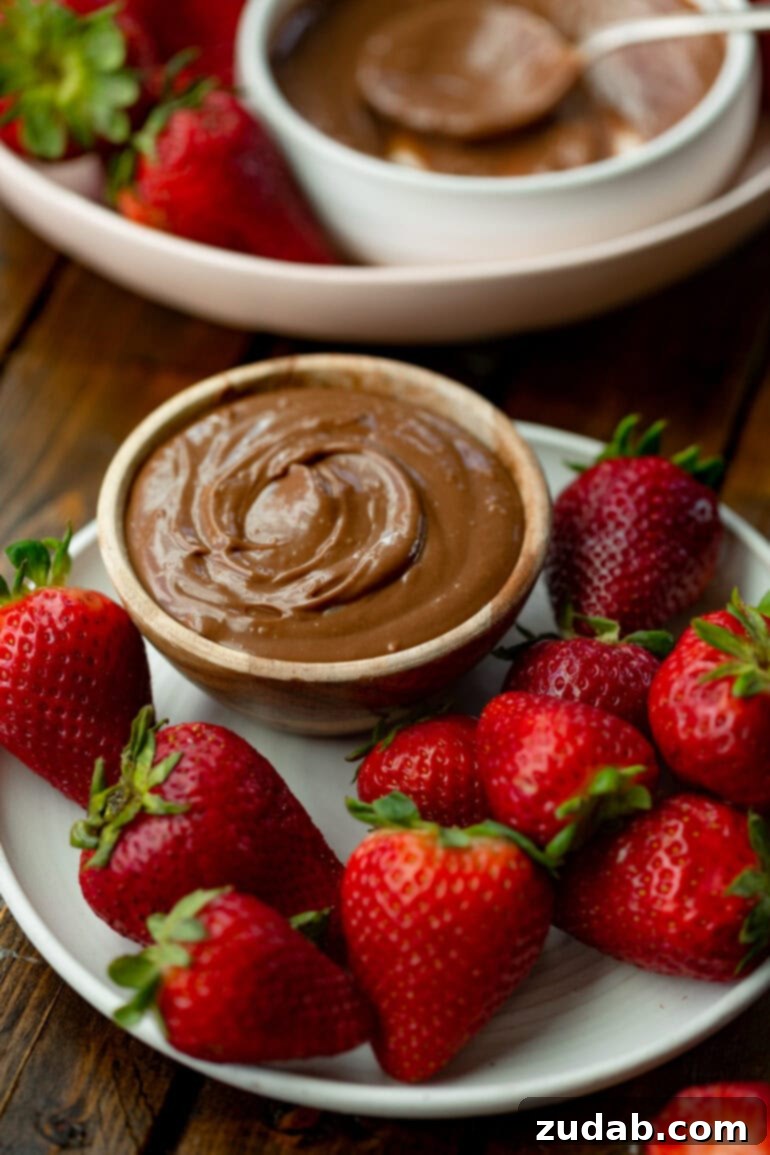 Guilt-Free Chocolate Strawberry Bliss 6 A large white plate holding a small bowl of rich chocolate yogurt dip, completely surrounded by a generous scattering of whole, bright red strawberries, ready to be enjoyed.