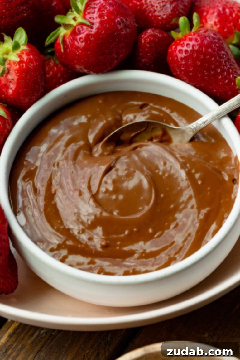 Guilt-Free Chocolate Strawberry Bliss 7 A bowl of creamy chocolate yogurt fruit dip being gently stirred with a spoon, highlighting its smooth and inviting texture, perfect for a healthy snack.