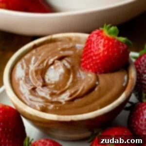 A small bowl filled with creamy chocolate yogurt dip with a whole strawberry dipped in it and strawberries scattered all around it, as featured in the recipe card.
