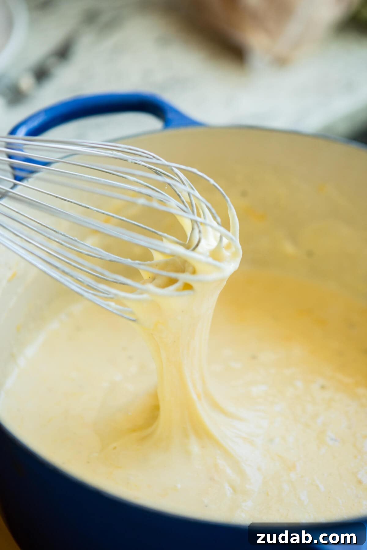 Loaded Chicken Bacon Ranch Mac and Cheese 4 cheese sauce for mac and cheese in a blue dutch oven with a whisk resting on top, creamy and ready for pasta