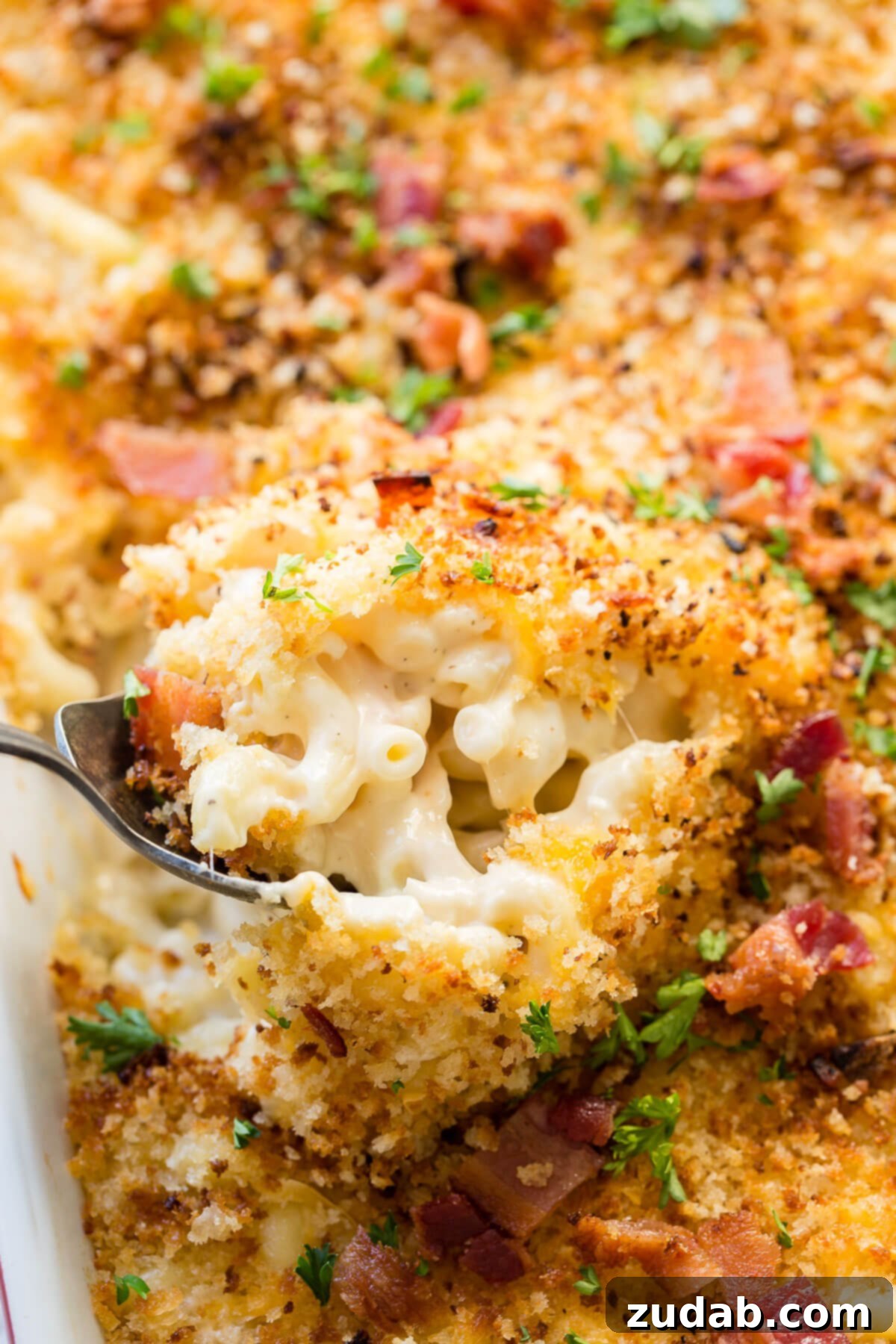 Loaded Chicken Bacon Ranch Mac and Cheese 8 close up of a spoon digging into a pan of chicken bacon mac and cheese, showing the creamy texture and delicious layers