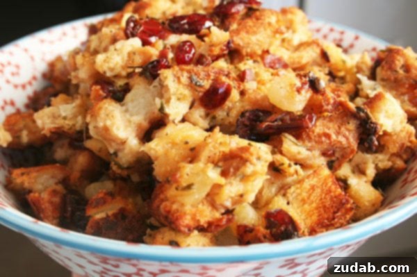 Sweet and Tangy Apple Cranberry Stuffing 4 A serving of Apple Cranberry Stuffing on a plate, garnished with fresh herbs