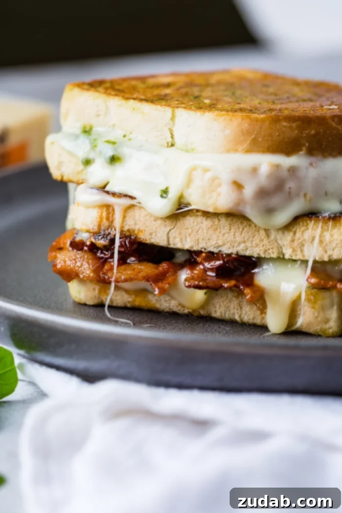 Mediterranean Bacon Pesto Grilled Cheese 8 Close-up of a Sun Dried Tomato Bacon Pesto Grilled Cheese, highlighting the melted cheese and fillings