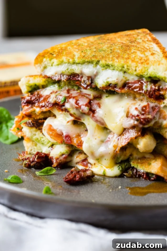 Mediterranean Bacon Pesto Grilled Cheese 10 A final close-up of a cut Sun Dried Tomato Bacon Pesto Grilled Cheese with melted cheese and basil