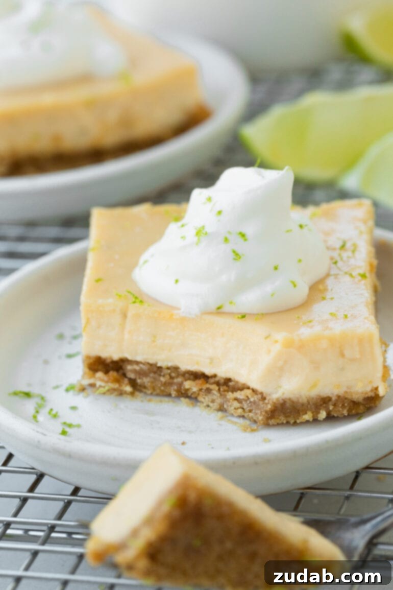 Zesty Key Lime Bars 3 A photo of a piece of torta de limao on a small dessert plate with a corner of the bar removed and scooped up with a fork.