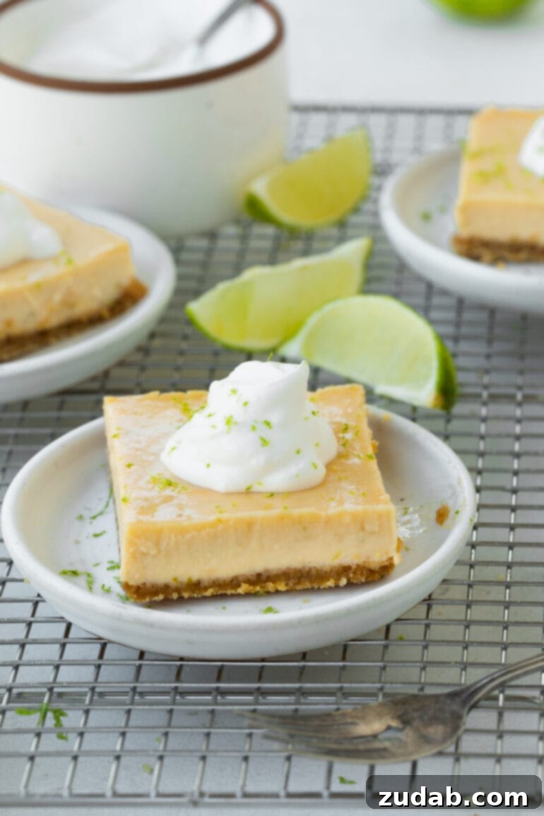 Zesty Key Lime Bars 4 A photo of a small dessert plate topped with a Key Lime bar with lime wedges scattered around it and other plates of dessert in the background
