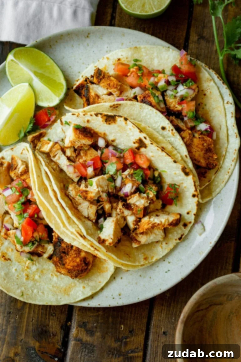 Quick and Delicious 30-Minute Grilled Chicken Tacos 2 A photo of three grilled chicken tacos, beautifully arranged in corn tortillas and generously topped with vibrant, fresh pico de gallo, ready to be enjoyed as a healthy and satisfying meal.