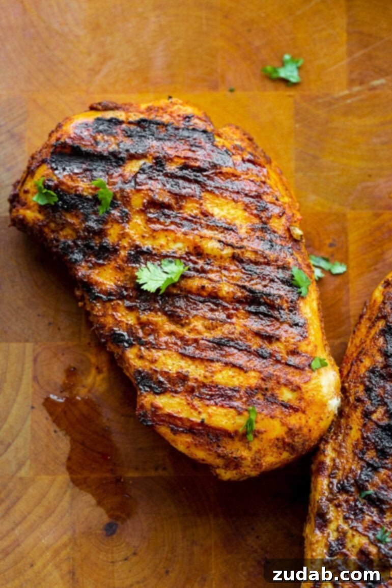Quick and Delicious 30-Minute Grilled Chicken Tacos 4 A photo of a perfectly grilled and seasoned chicken breast resting on a rustic wooden cutting board, showcasing the delicious char and tender texture before being chopped for tacos.