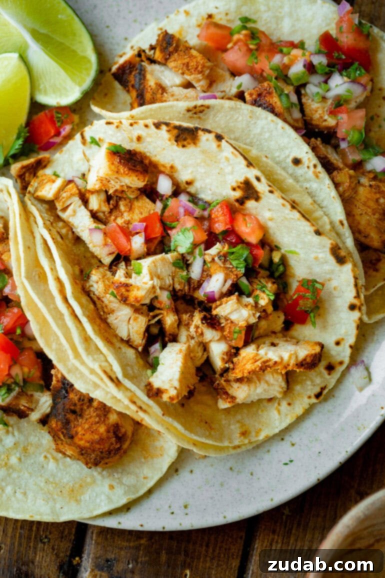 Quick and Delicious 30-Minute Grilled Chicken Tacos 6 A top-down view of several grilled chicken tacos arranged invitingly on a platter, showcasing the golden tortillas, succulent chicken, and vibrant pico de gallo, ready for serving.