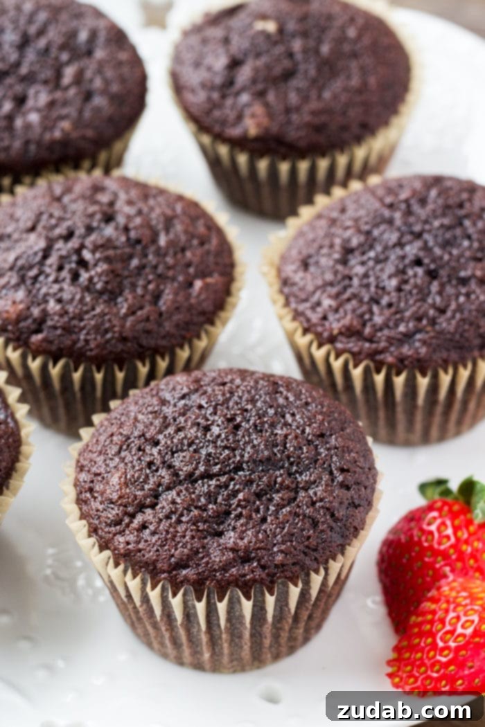 A tantalizing photo of several freshly baked chocolate cupcakes, perfectly cooled and awaiting their delightful strawberry frosting.