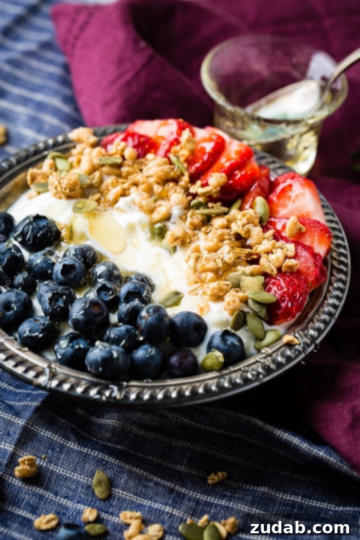 Homemade Instant Pot Yogurt 2 Bowl of instant pot yogurt with fresh blueberries, strawberries, pepitas, granola and a drizzle of honey in a vintage bowl with blue and purple napkins.