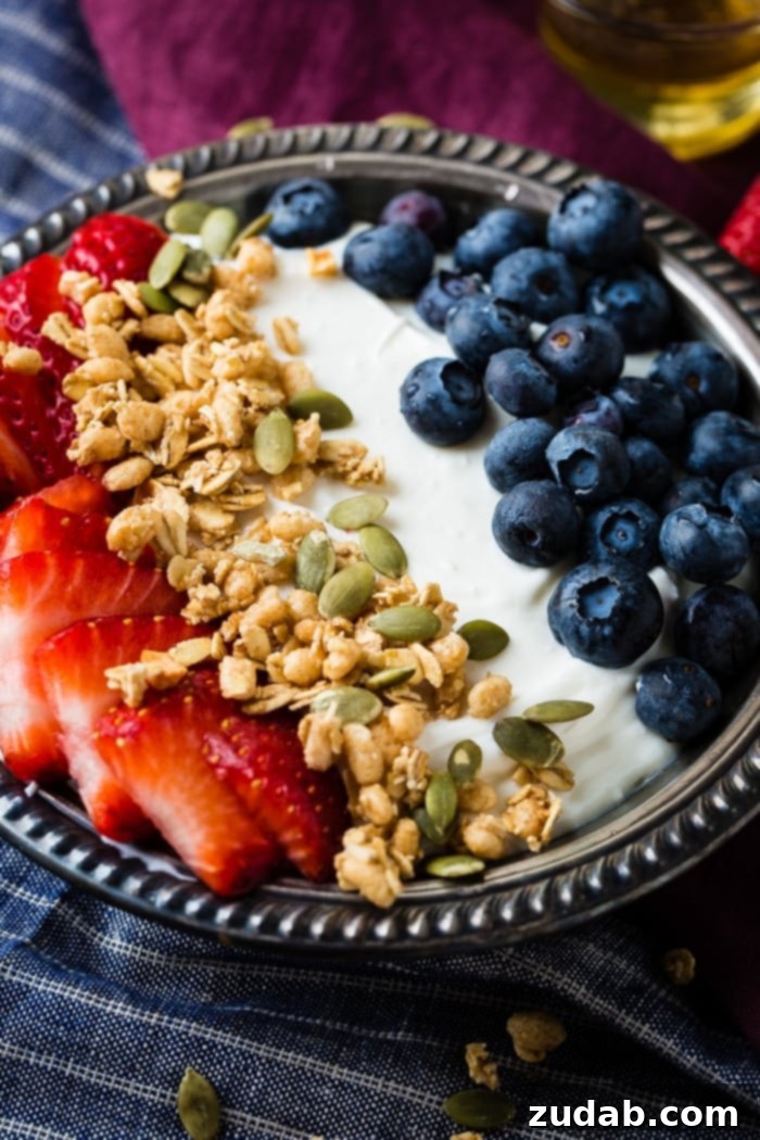 Homemade Instant Pot Yogurt 3 Bowl of instant pot yogurt with fresh blueberries, strawberries, pepitas, granola and a drizzle of honey in a vintage bowl with blue and purple napkins.