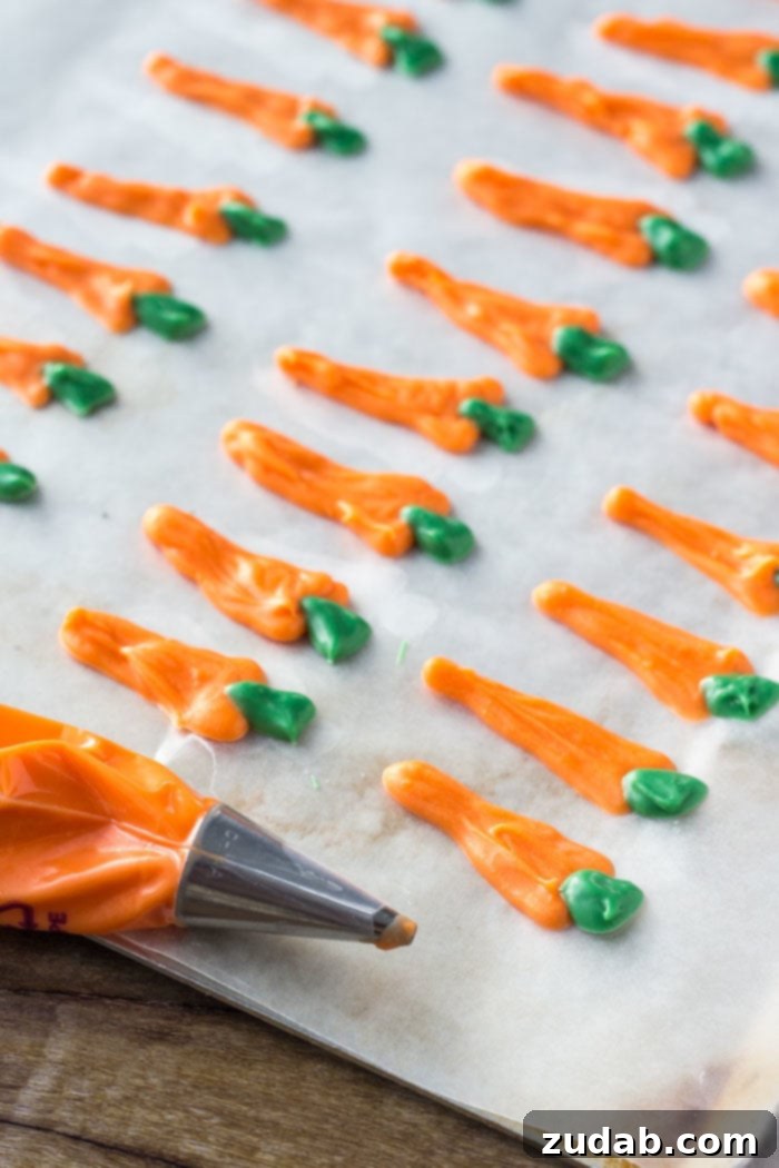 Candy Melt Carrot Decorations Hand-piped orange and green candy melt carrots drying on wax paper, ready to be used as cupcake toppers