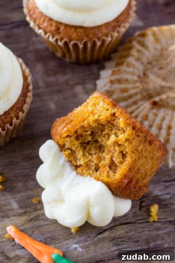 Delicious Carrot Cake Cupcake Detail A delectable carrot cake cupcake, partially eaten, lying on its side, showcasing its moist interior and creamy frosting
