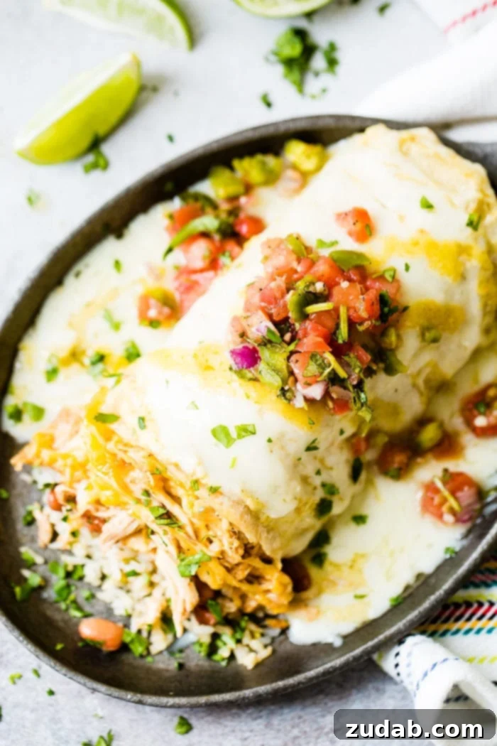 Zesty Honey-Lime Smothered Chicken Burritos 4 Three chicken burritos lined up in a cast iron skillet. Each burrito is generously topped with melted cheese, vibrant salsa, and fresh cilantro, highlighting the rich, comforting fillings.