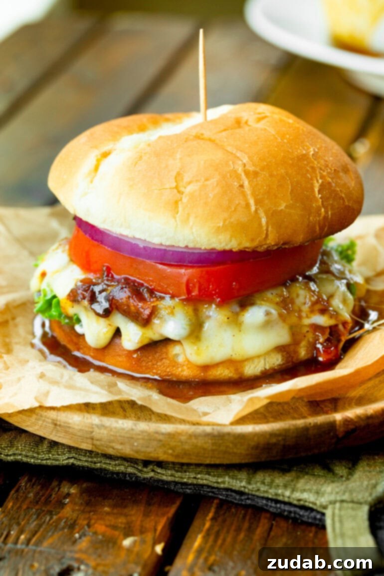 Tropical Heat Turkey Burgers 4 A vibrant, fully assembled pineapple jalapeño turkey burger, showcasing melted cheese, a juicy tomato slice, crisp red onion, and the tangy sauce dripping enticingly down the sides.