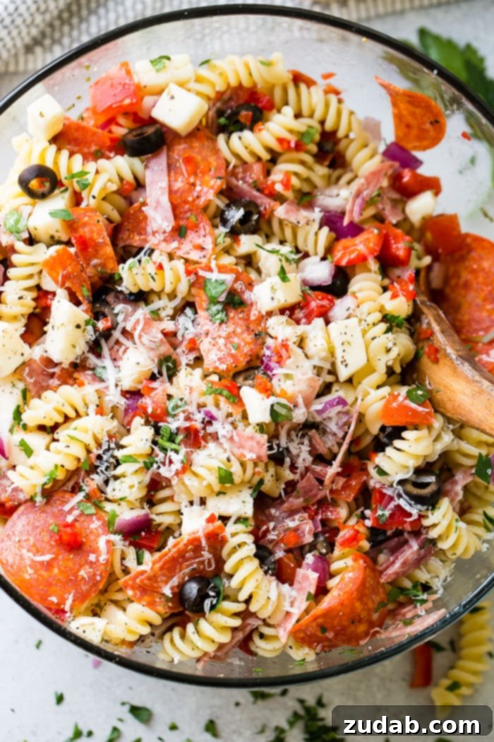 Effortless Italian Pasta Salad 2 A glass bowl of quick and easy Italian pasta salad recipe with homemade Italian dressing. Rotini pasta with pepperoni, salsami, black olives, parmesan cheese, mozzarella cheese, peppers, dressing and red onions!