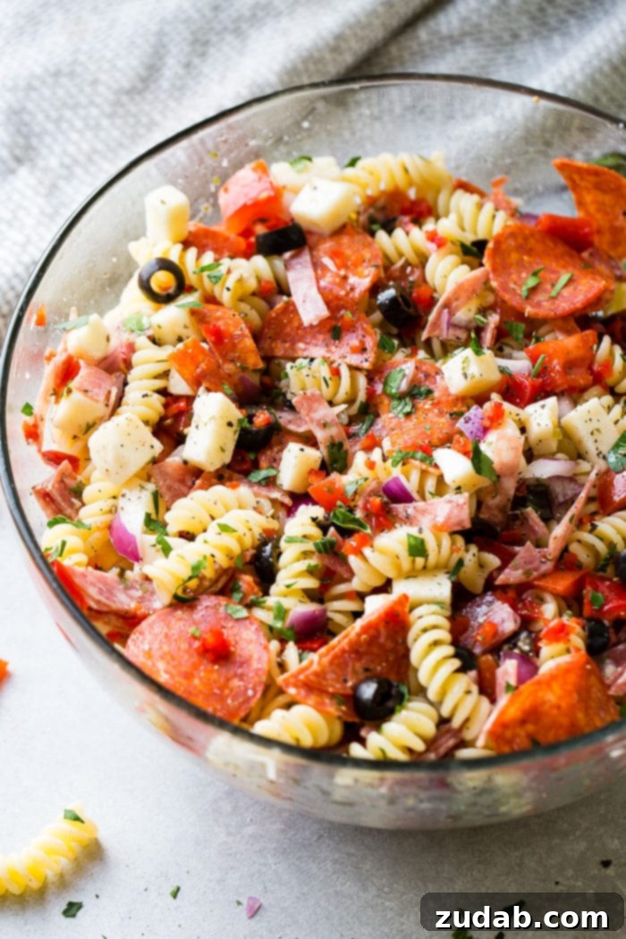 Effortless Italian Pasta Salad 3 A glass bowl of quick and easy Italian pasta salad recipe with homemade Italian dressing. Rotini pasta with pepperoni, salsami, black olives, parmesan cheese, mozzarella cheese, peppers, dressing and red onions!