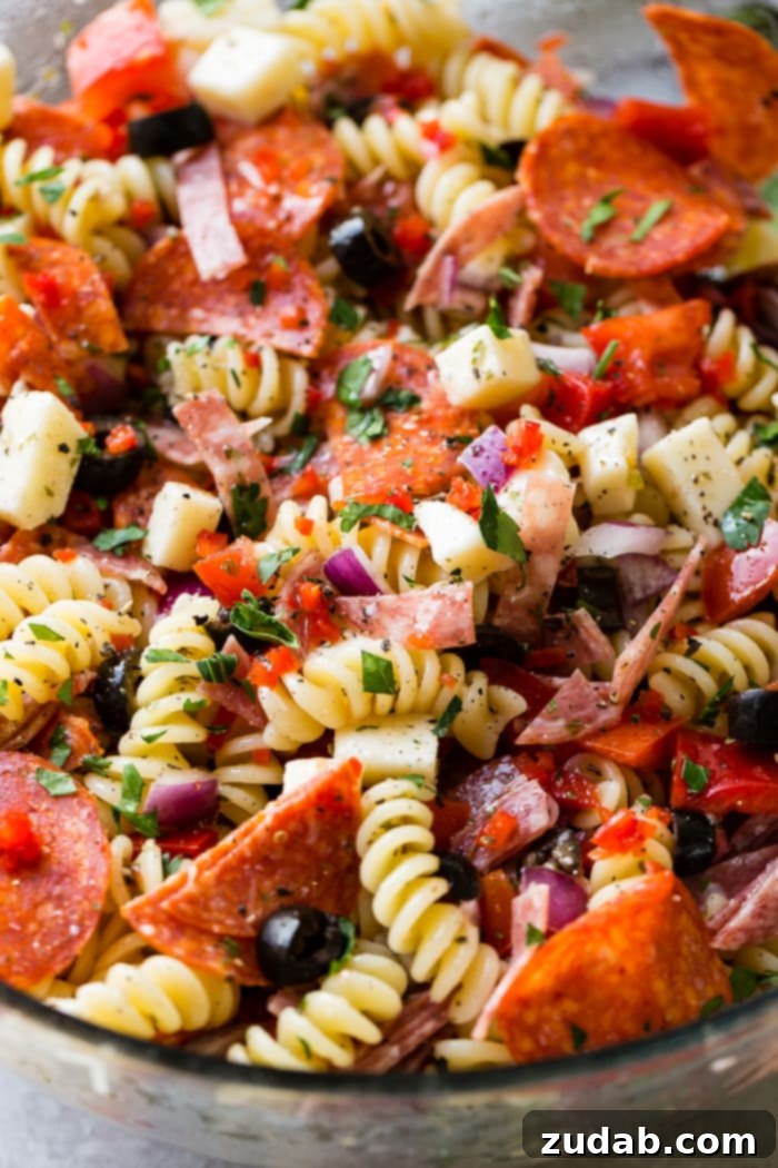 Effortless Italian Pasta Salad 4 A close up of rotini pasta salad with pepperoni, mozzarella and parmesan cheese, black olives, red peppers, salami and more!