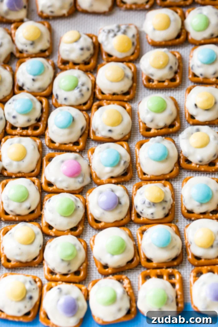 Easter M&M Pretzel Bites 4 A single mini pretzel topped with a perfectly softened Hershey's Cookies 'n' Cream Hug and a pastel Easter M&M, highlighting the simple elegance of this homemade treat.