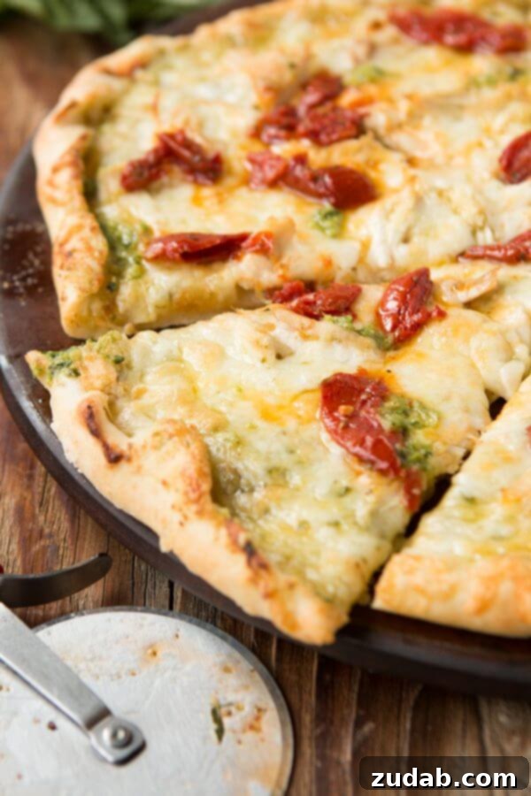 The Irresistible Combination of Pesto, Chicken, and Sun-Dried Tomatoes on Pizza Freshly baked Creamy Pesto Chicken Pizza adorned with vibrant sun-dried tomatoes.